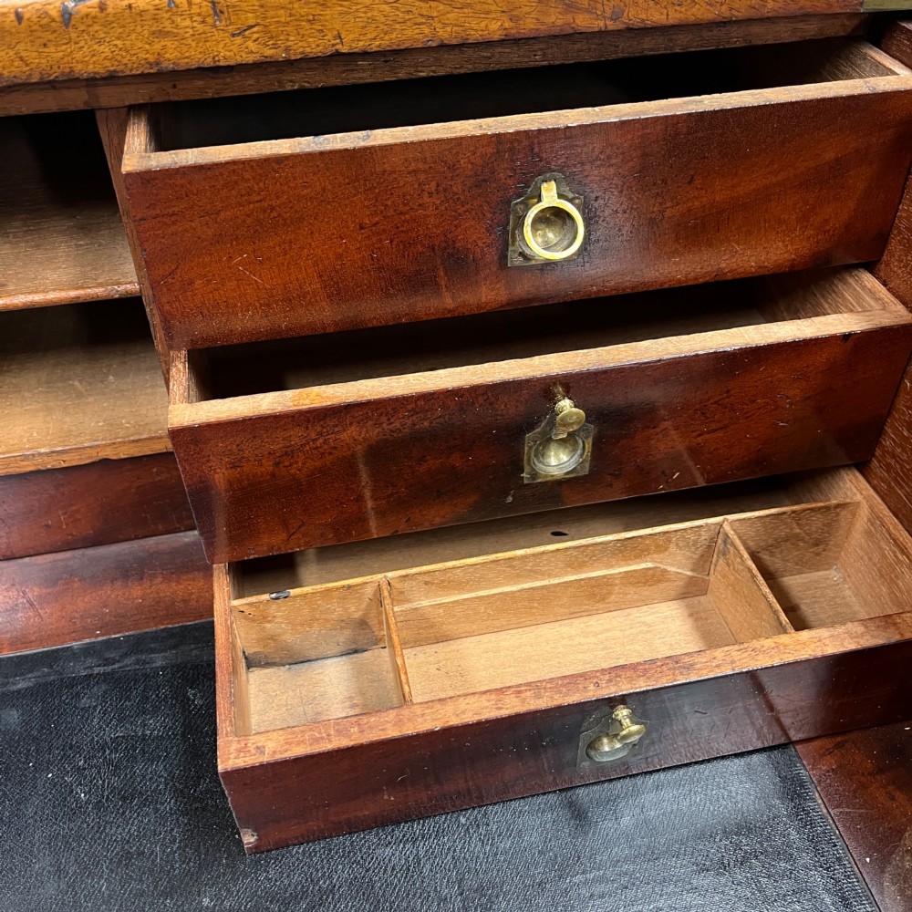A 19th-century mahogany military campaign secretaire chest featuring four drawers with recessed brass handles and brass corner straps, resting on turned feet. View VI