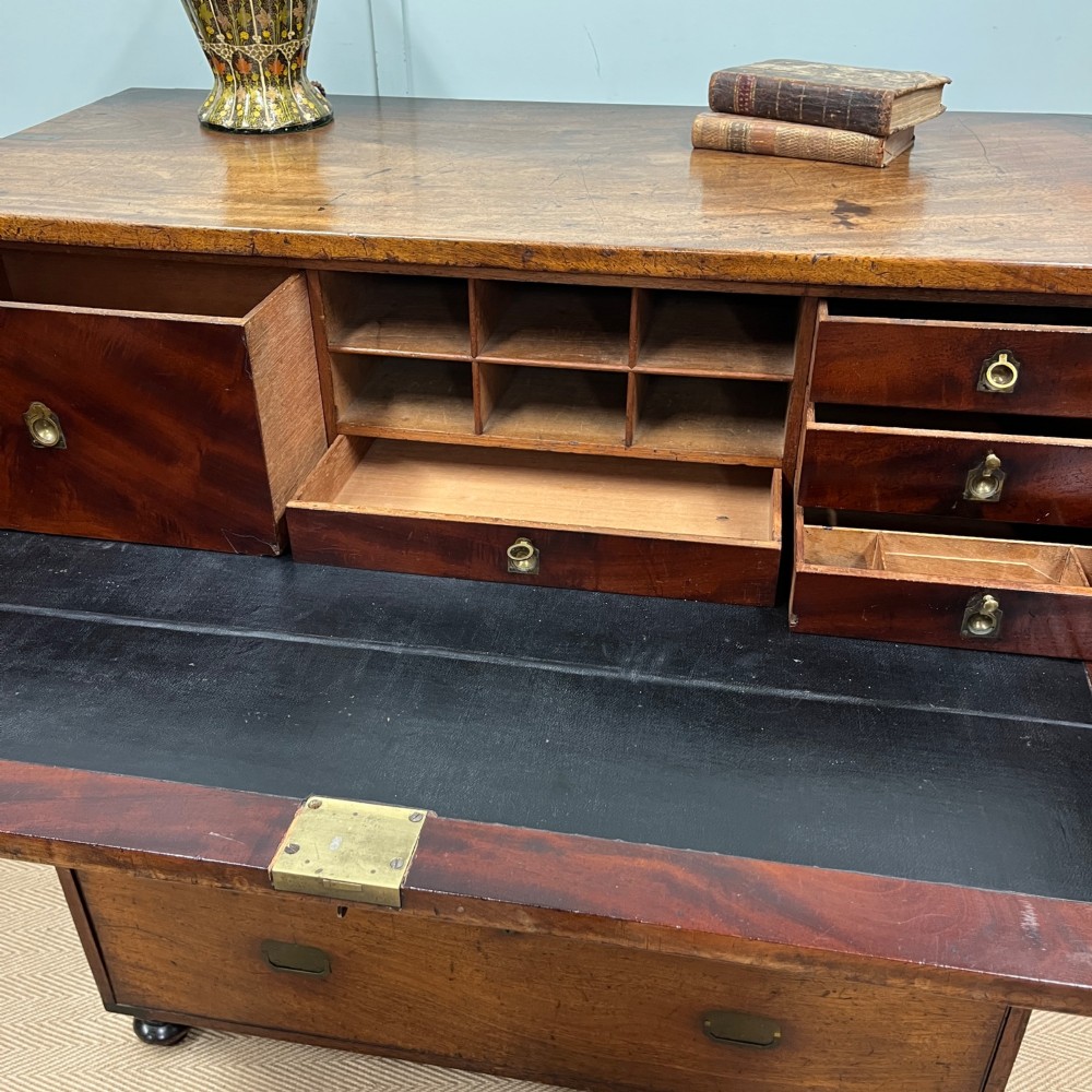 A 19th-century mahogany military campaign secretaire chest featuring four drawers with recessed brass handles and brass corner straps, resting on turned feet. View VII
