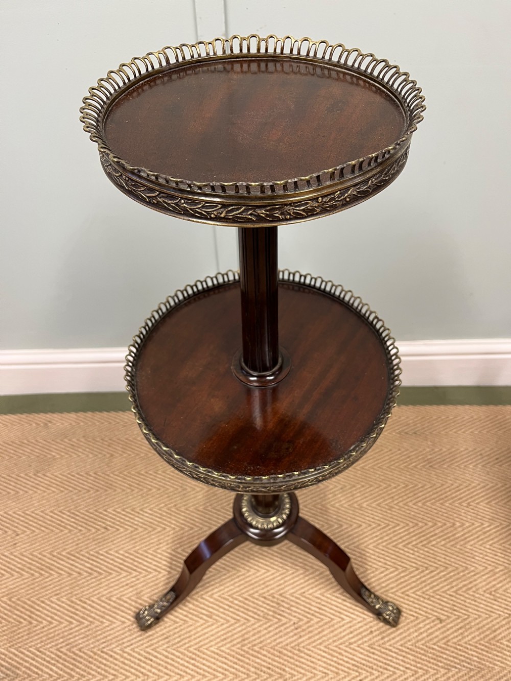 A two-tier dark mahogany dumb waiter featuring pierced brass galleries, a fluted central stem, and a tripod base with brass feet. View VIII