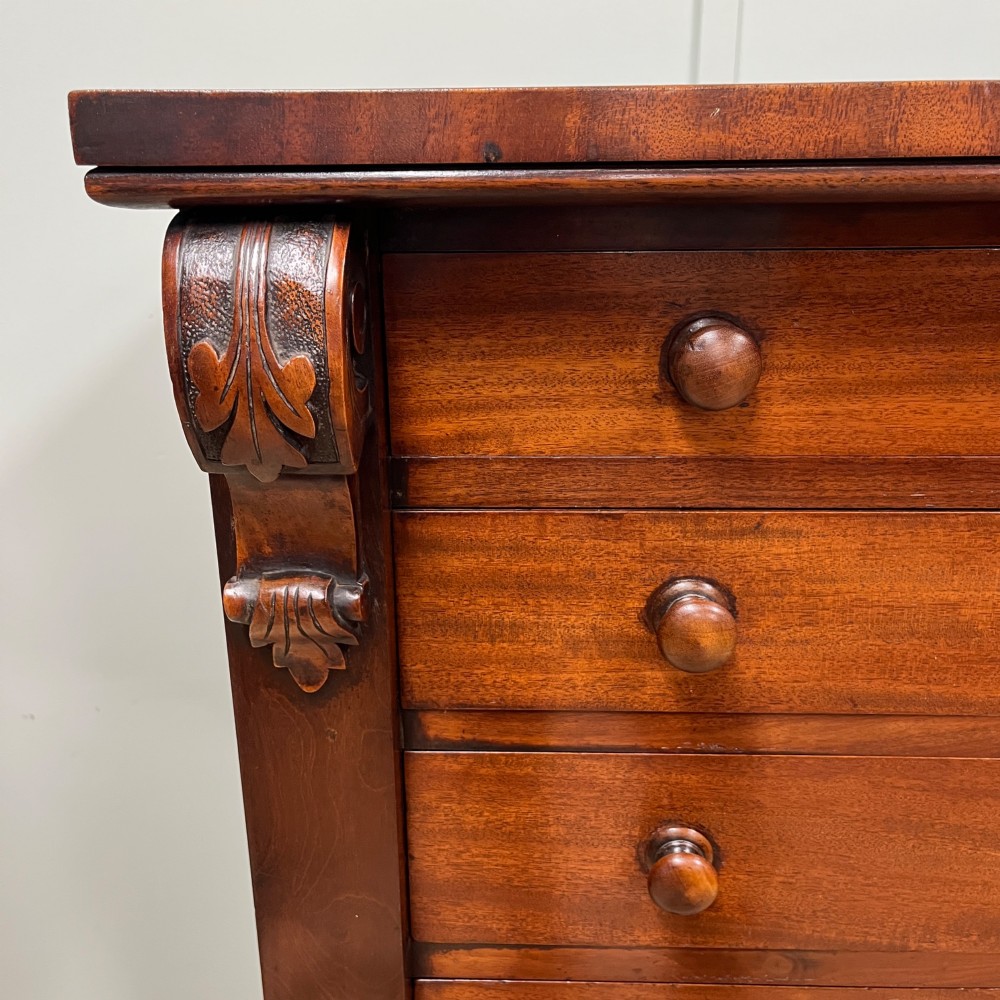 A tall Victorian mahogany Wellington chest featuring eight graduated drawers with turned wooden knobs, carved corbels at the top, and a side hinged locking flap on a plinth base. View II