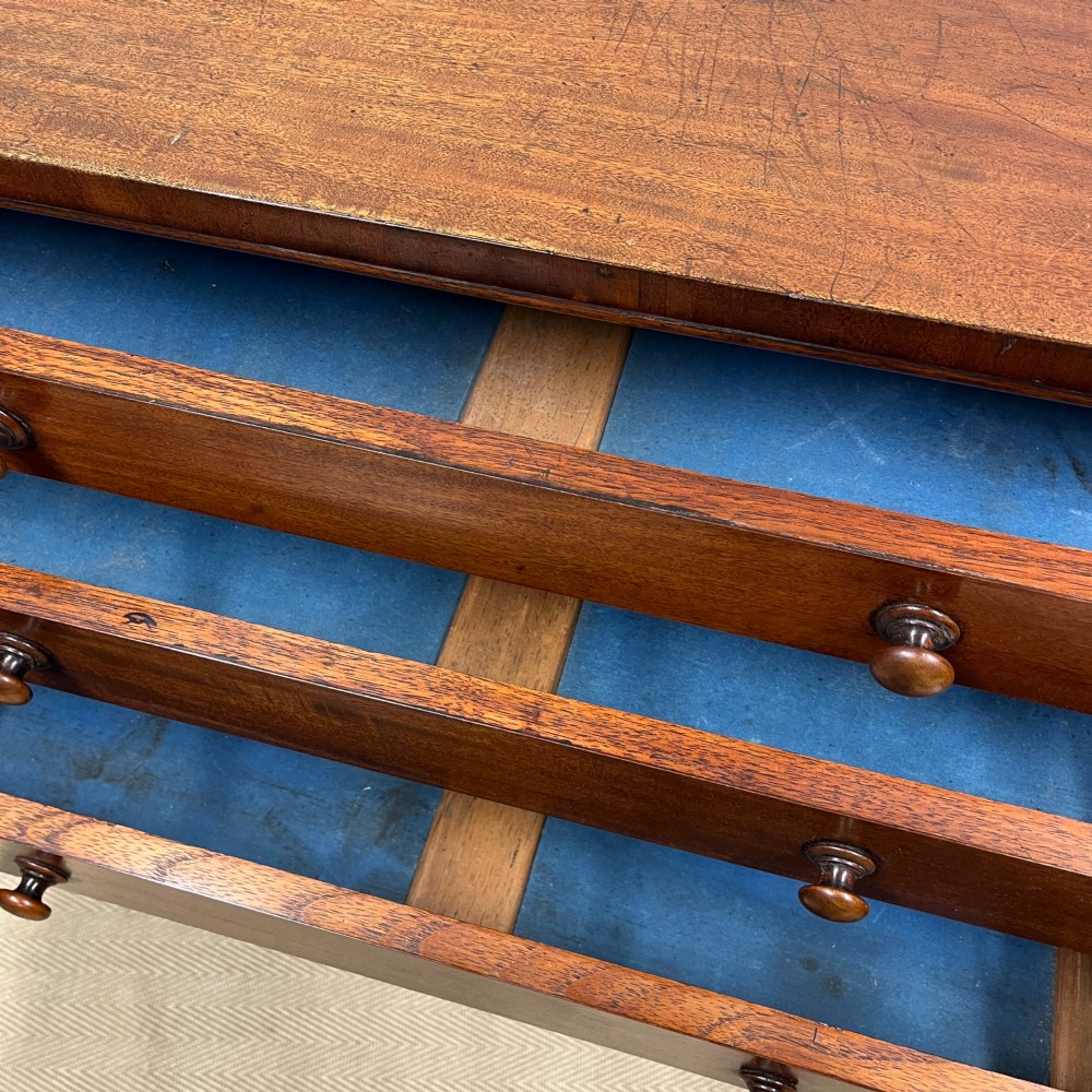A tall Victorian mahogany Wellington chest featuring eight graduated drawers with turned wooden knobs, carved corbels at the top, and a side hinged locking flap on a plinth base. View VI