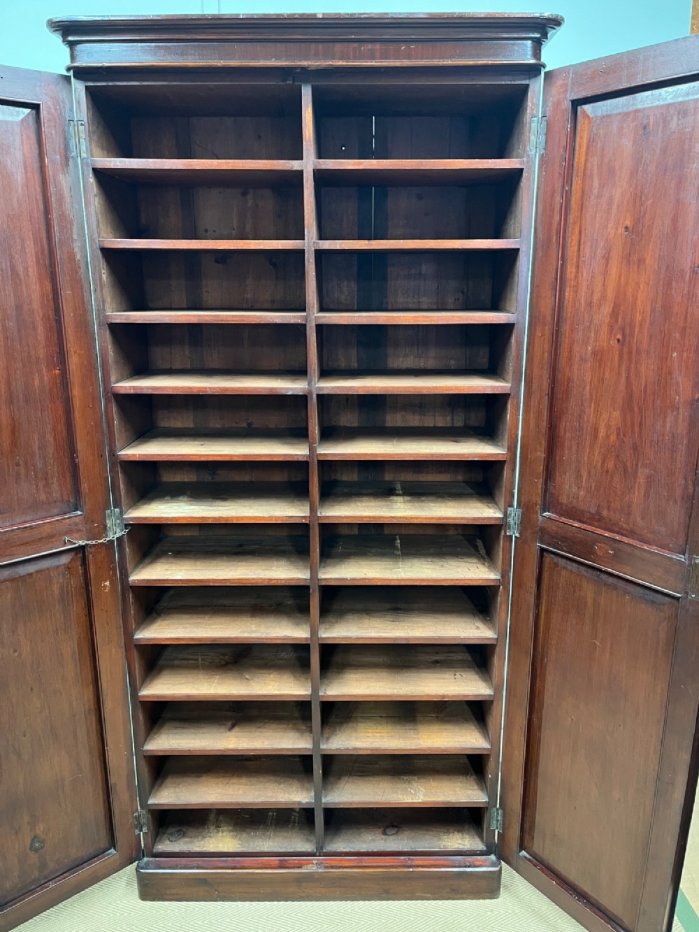 A tall, slim 19th-century mahogany cupboard featuring twin panelled doors and a solid plinth base. View IV