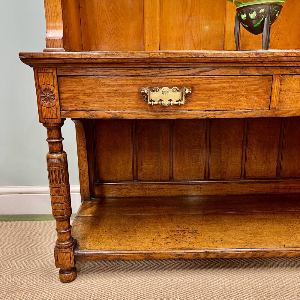 A 19th-century oak dresser featuring a three-tiered open shelf rack above two drawers with brass swan-neck handles and an open pot board base on turned legs. View III
