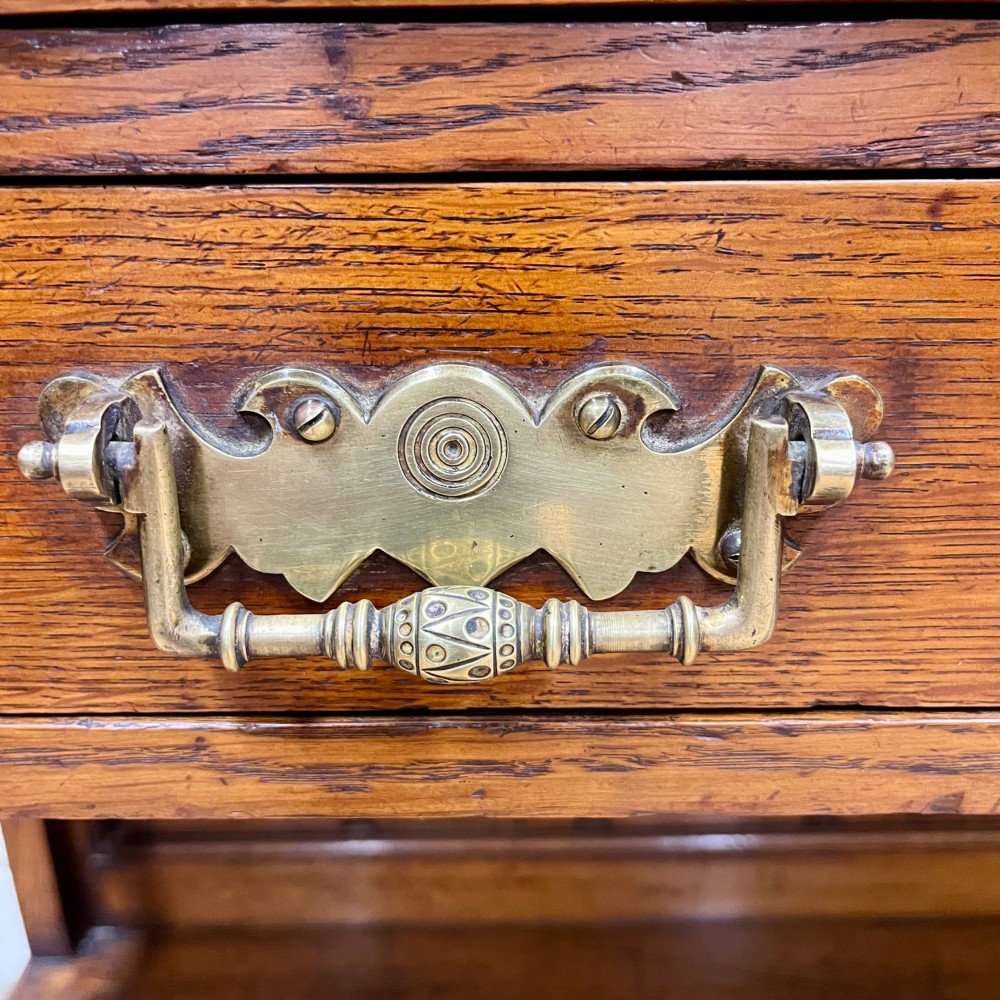 A 19th-century oak dresser featuring a three-tiered open shelf rack above two drawers with brass swan-neck handles and an open pot board base on turned legs. View IV