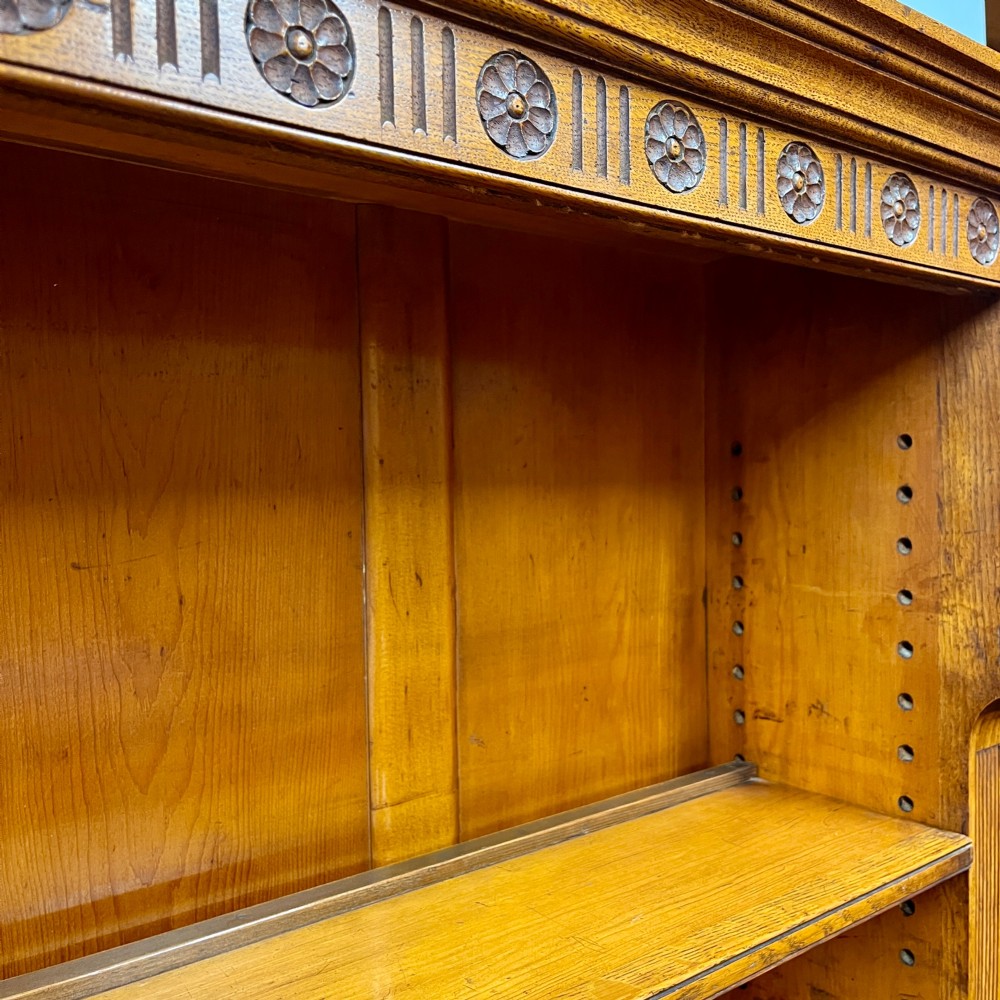A 19th-century oak dresser featuring a three-tiered open shelf rack above two drawers with brass swan-neck handles and an open pot board base on turned legs. View V