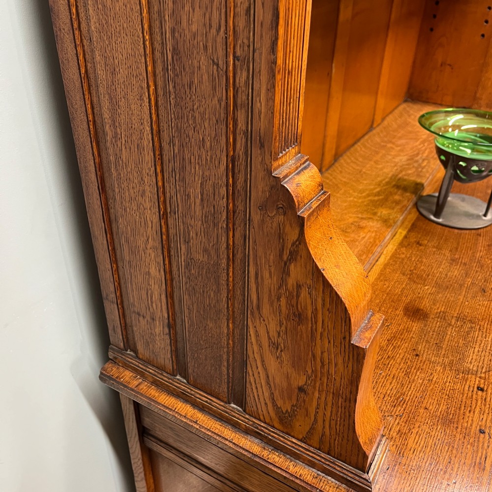A 19th-century oak dresser featuring a three-tiered open shelf rack above two drawers with brass swan-neck handles and an open pot board base on turned legs. View VII