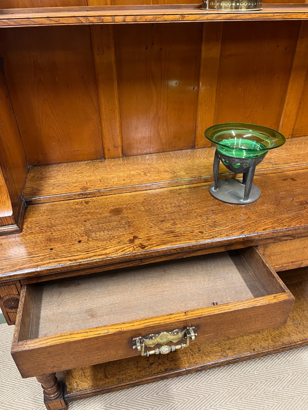 A 19th-century oak dresser featuring a three-tiered open shelf rack above two drawers with brass swan-neck handles and an open pot board base on turned legs. View XII