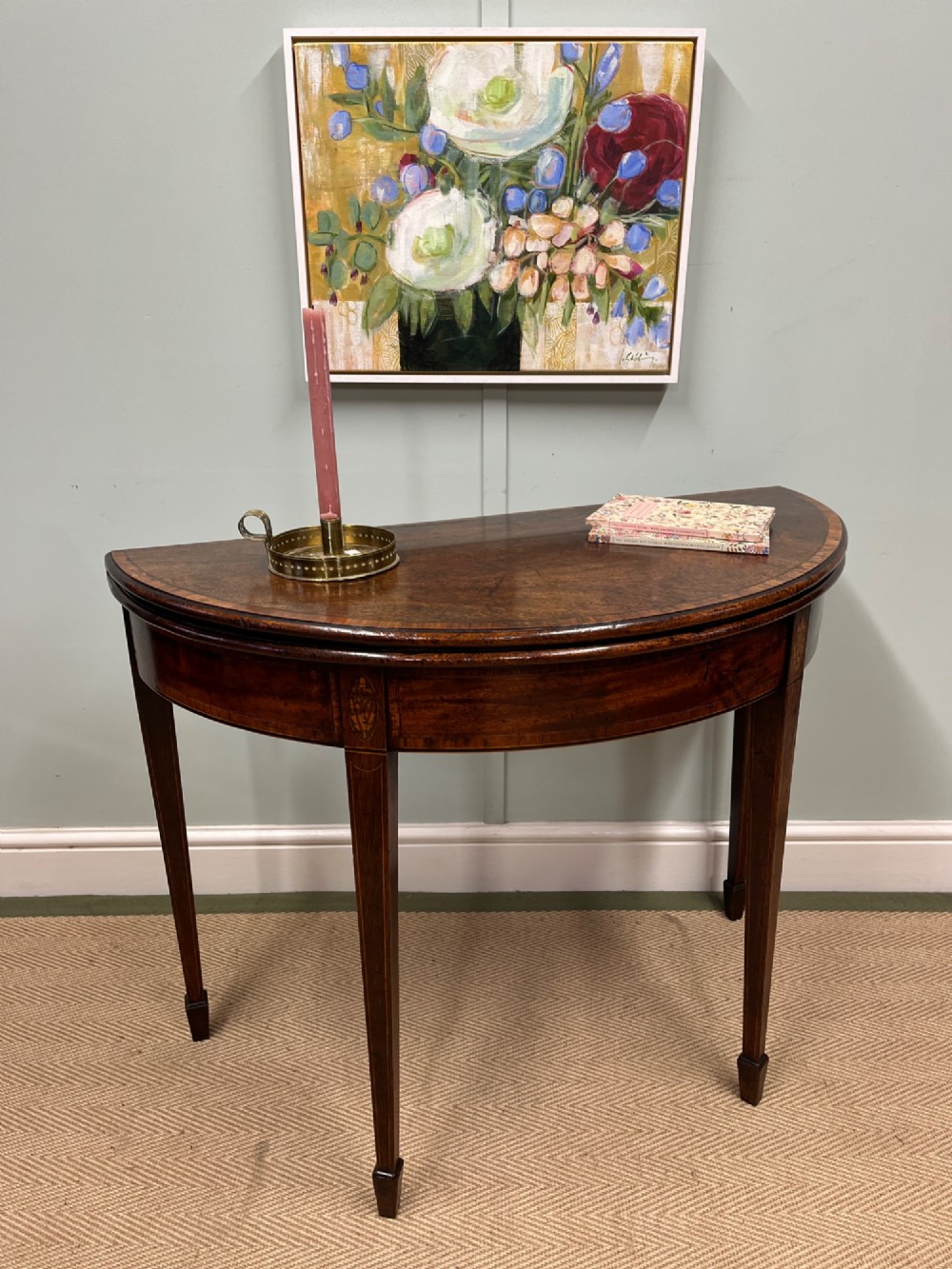 A Georgian mahogany demilune tea table featuring wood stringing and four tapered square legs.
