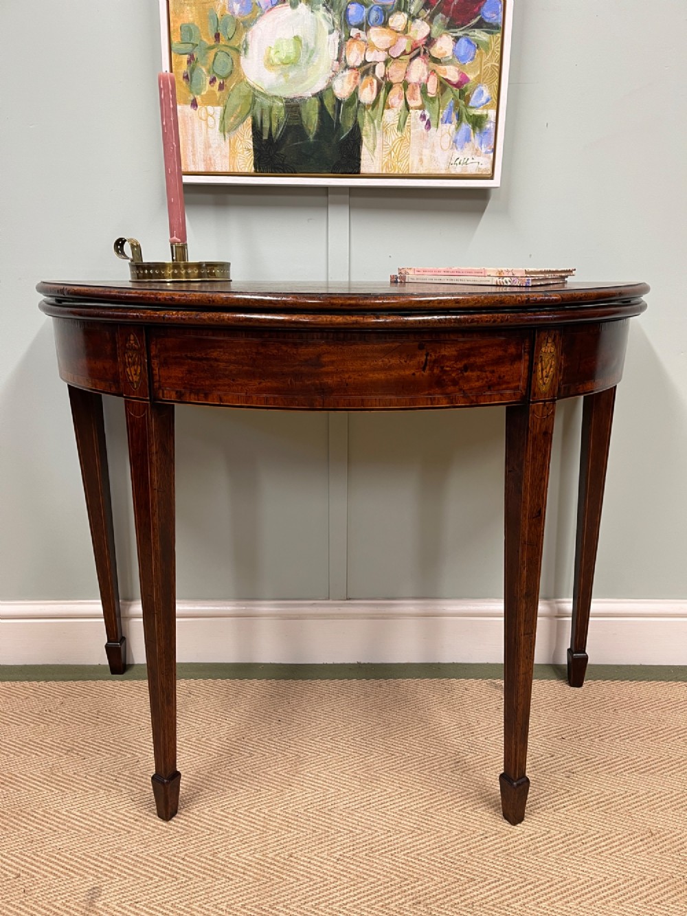 A Georgian mahogany demilune tea table featuring wood stringing and four tapered square legs. View II