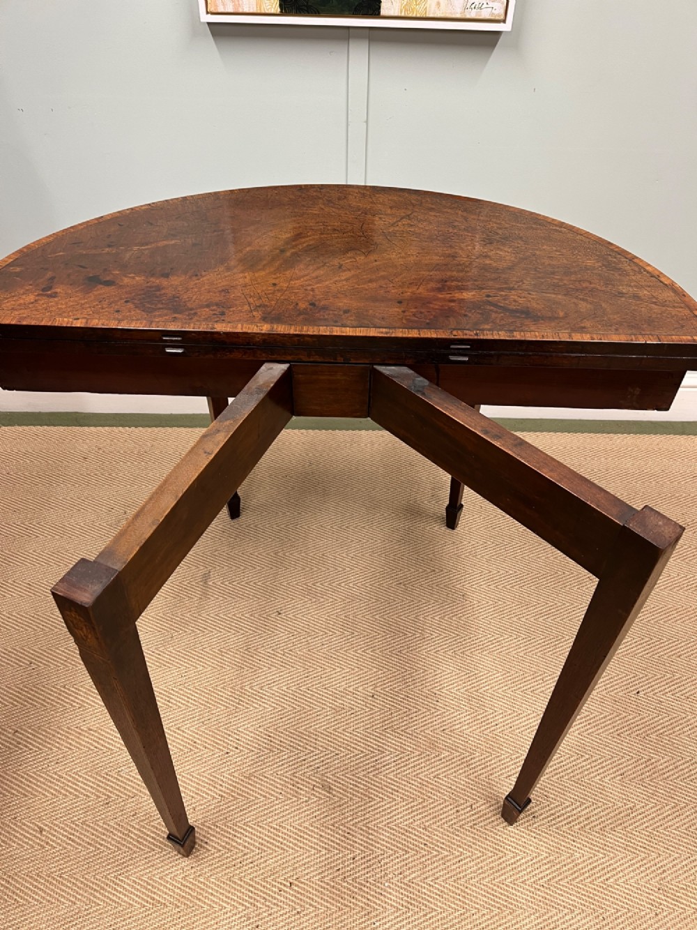 A Georgian mahogany demilune tea table featuring wood stringing and four tapered square legs. View VI