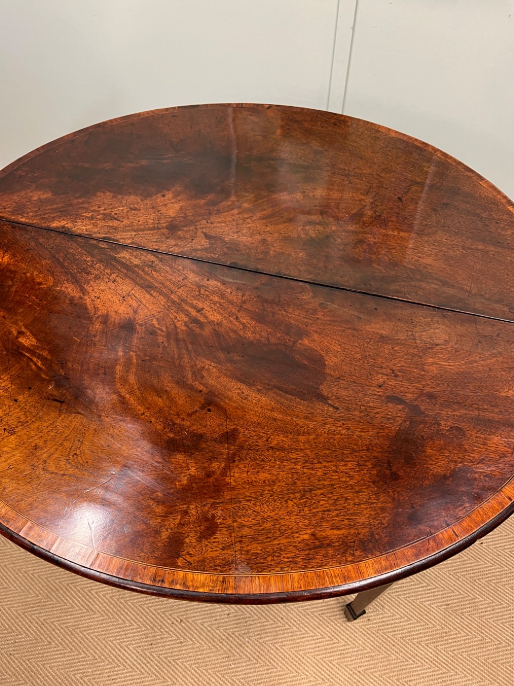 A Georgian mahogany demilune tea table featuring wood stringing and four tapered square legs. View VII