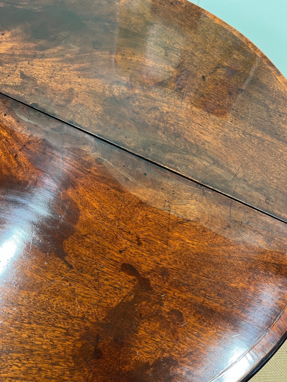 A Georgian mahogany demilune tea table featuring wood stringing and four tapered square legs. View VIII