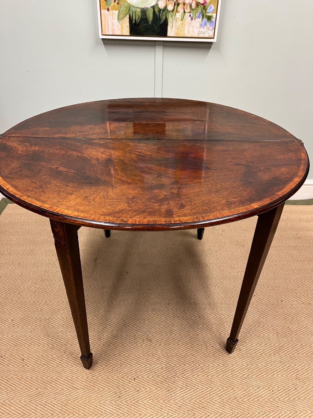 A Georgian mahogany demilune tea table featuring wood stringing and four tapered square legs. View IX