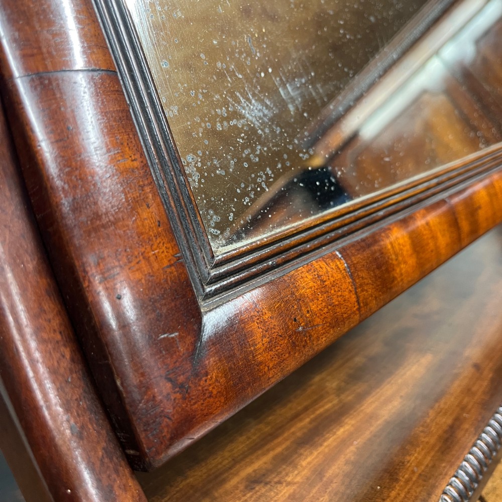 A 19th-century rectangular flame mahogany toilet mirror with a swivelling frame resting on a shaped platform base with carved edging. View VII