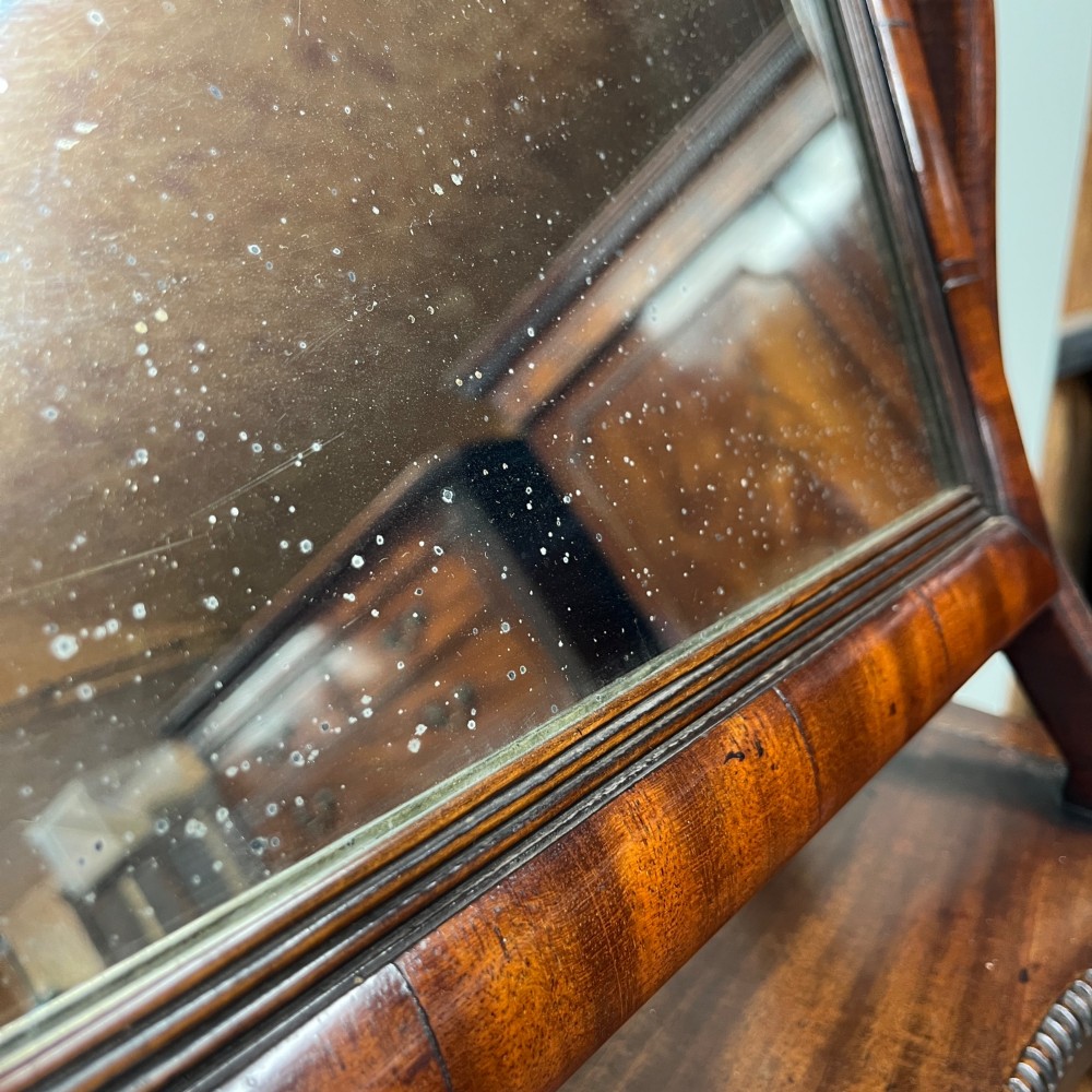 A 19th-century rectangular flame mahogany toilet mirror with a swivelling frame resting on a shaped platform base with carved edging. View VIII