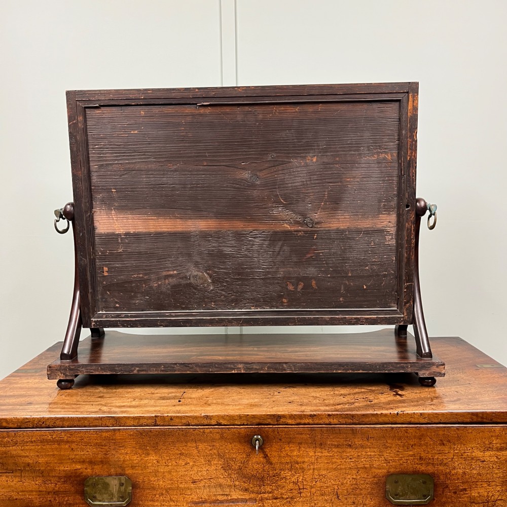 A 19th-century rectangular flame mahogany toilet mirror with a swivelling frame resting on a shaped platform base with carved edging. View XI