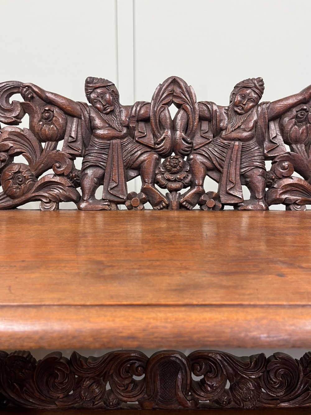 A 19th-century carved dark teak three-tier buffet featuring relief-carved backboard galleries with figurative motifs, supported on carved uprights and trestle feet. View II