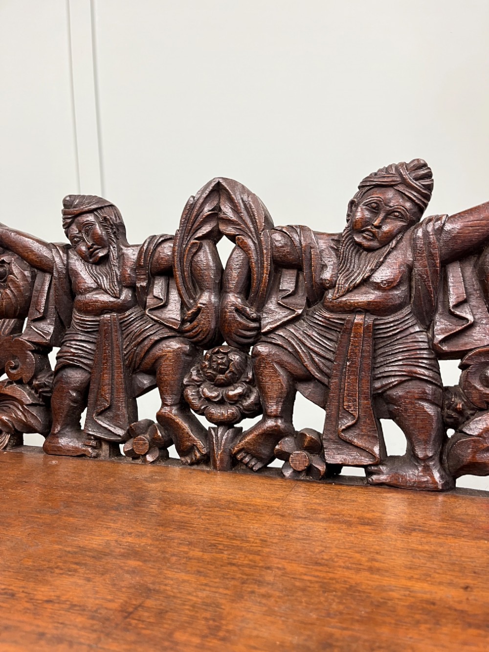 A 19th-century carved dark teak three-tier buffet featuring relief-carved backboard galleries with figurative motifs, supported on carved uprights and trestle feet. View VII