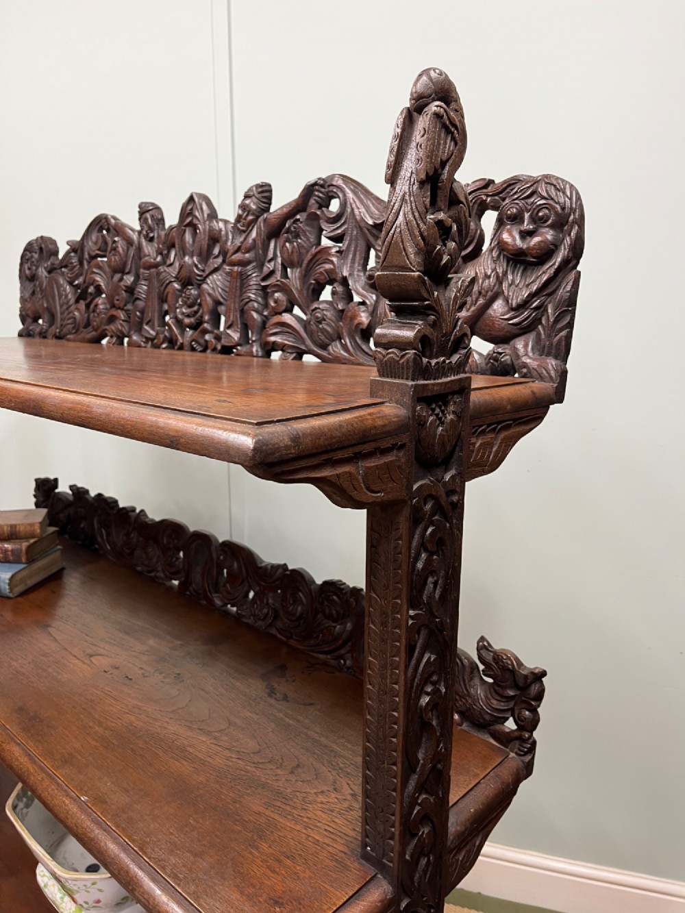 A 19th-century carved dark teak three-tier buffet featuring relief-carved backboard galleries with figurative motifs, supported on carved uprights and trestle feet. View VIII