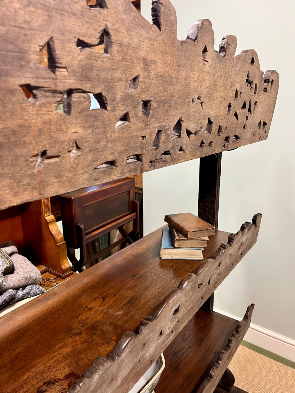 A 19th-century carved dark teak three-tier buffet featuring relief-carved backboard galleries with figurative motifs, supported on carved uprights and trestle feet. View IX
