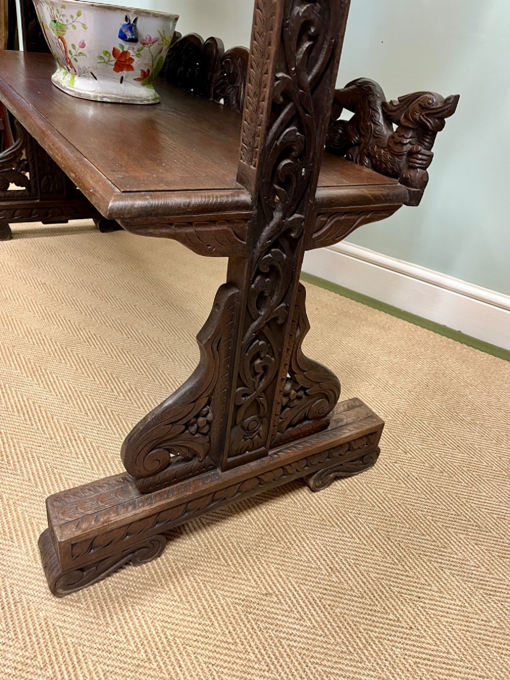 A 19th-century carved dark teak three-tier buffet featuring relief-carved backboard galleries with figurative motifs, supported on carved uprights and trestle feet. View XI