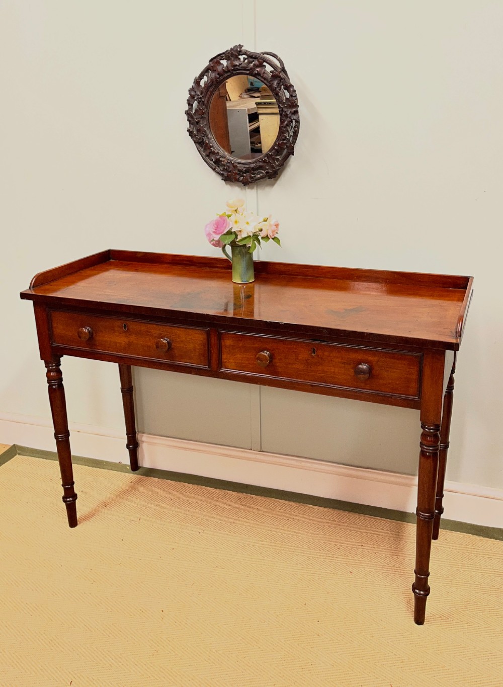 A 19th-century mahogany hall table with two frieze drawers, turned legs, and a raised gallery edge along the top.