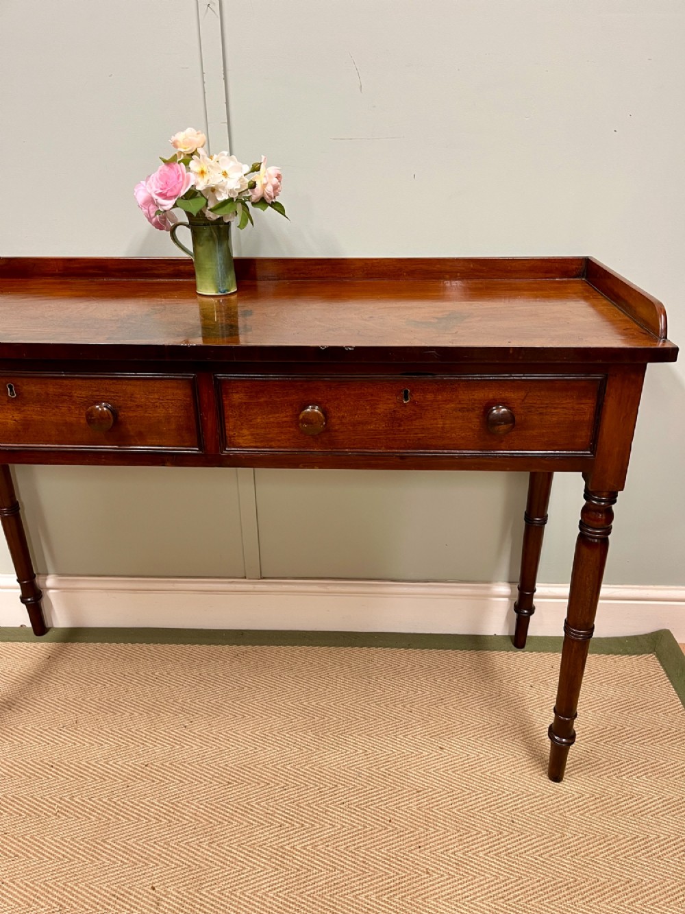 A 19th-century mahogany hall table with two frieze drawers, turned legs, and a raised gallery edge along the top. View II