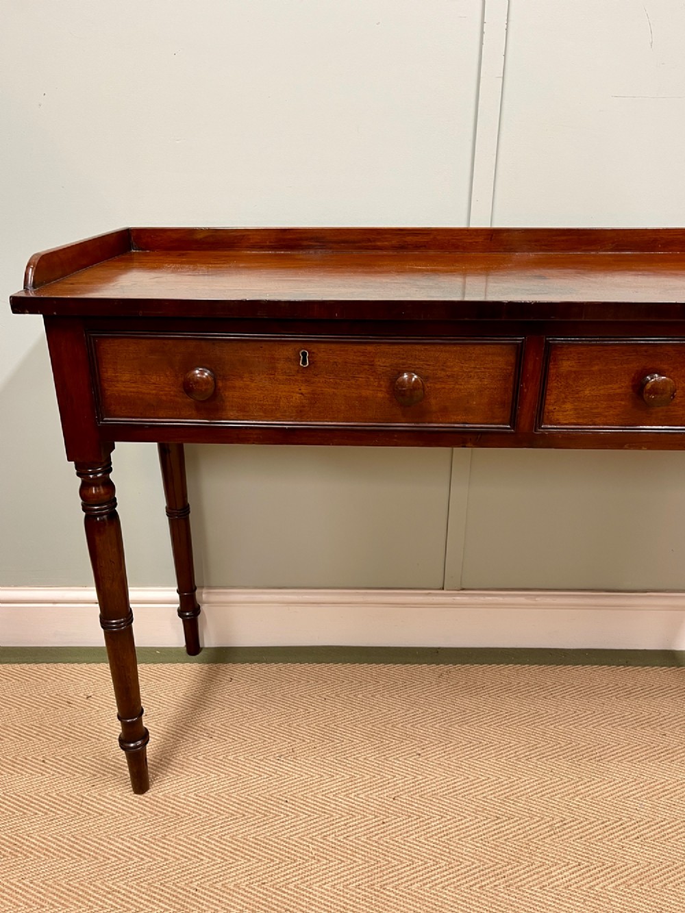 A 19th-century mahogany hall table with two frieze drawers, turned legs, and a raised gallery edge along the top. View V