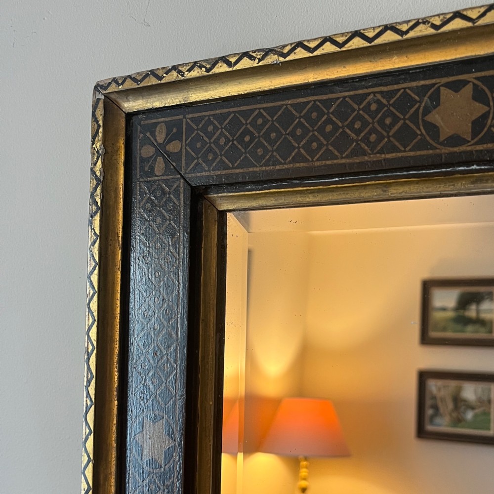 A large nineteenth-century rectangular wall mirror featuring a dark painted frame embellished with geometric motifs and a gilded outer border. View III