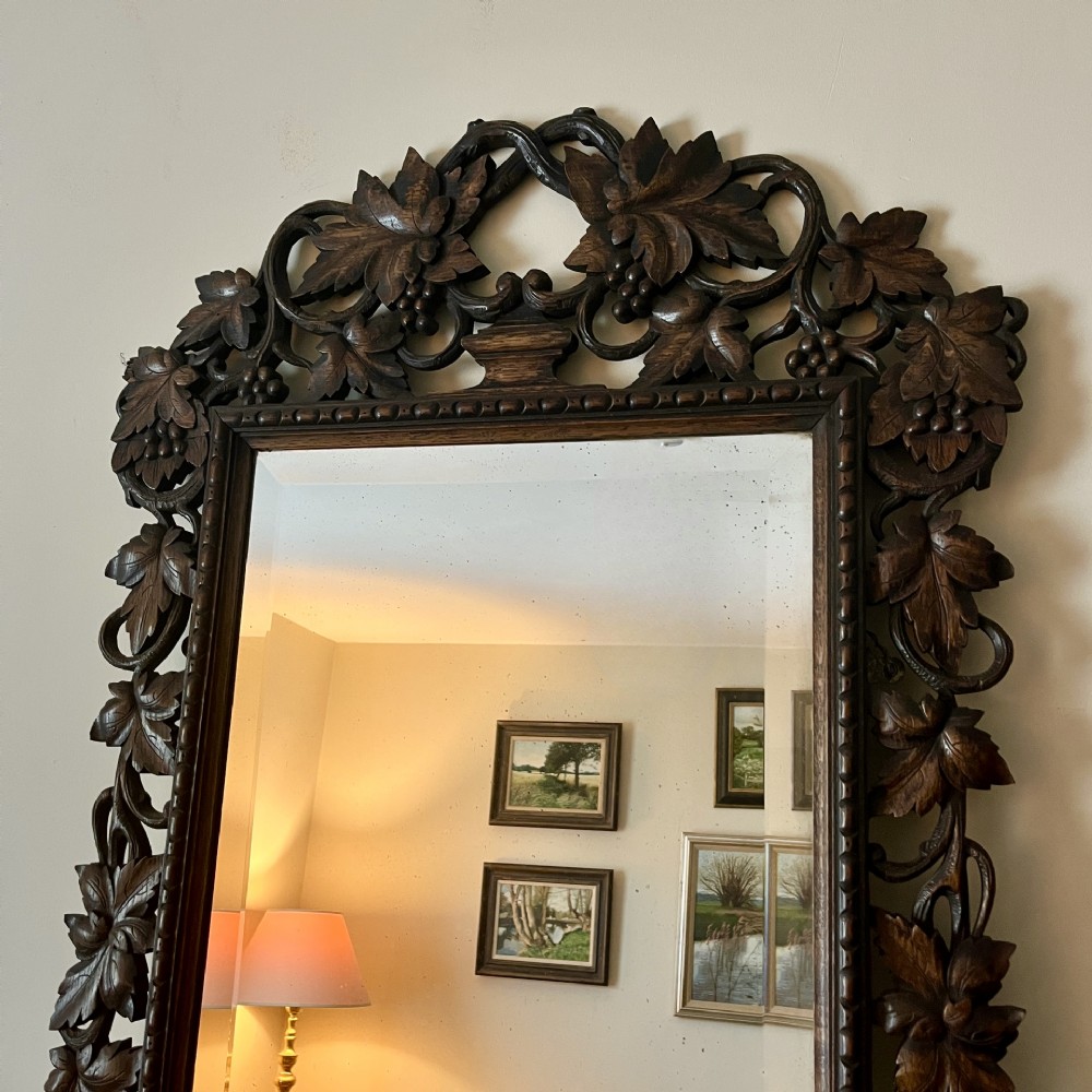 A rectangular 19th-century dark oak wall mirror set within an intricately carved openwork frame decorated with vine leaves and grape motifs. View II