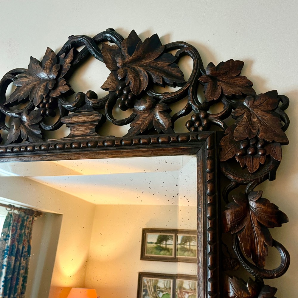 A rectangular 19th-century dark oak wall mirror set within an intricately carved openwork frame decorated with vine leaves and grape motifs. View III