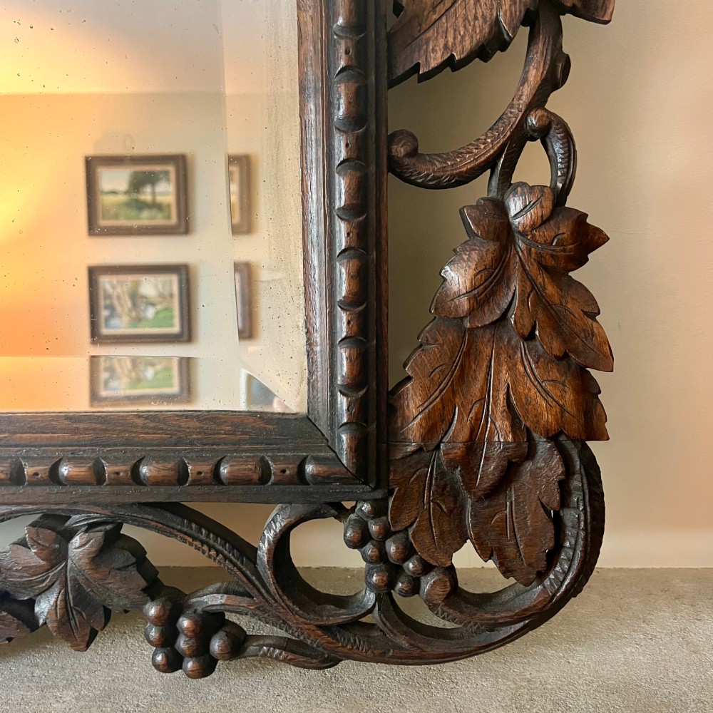 A rectangular 19th-century dark oak wall mirror set within an intricately carved openwork frame decorated with vine leaves and grape motifs. View V