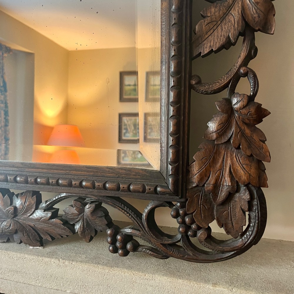 A rectangular 19th-century dark oak wall mirror set within an intricately carved openwork frame decorated with vine leaves and grape motifs. View VI