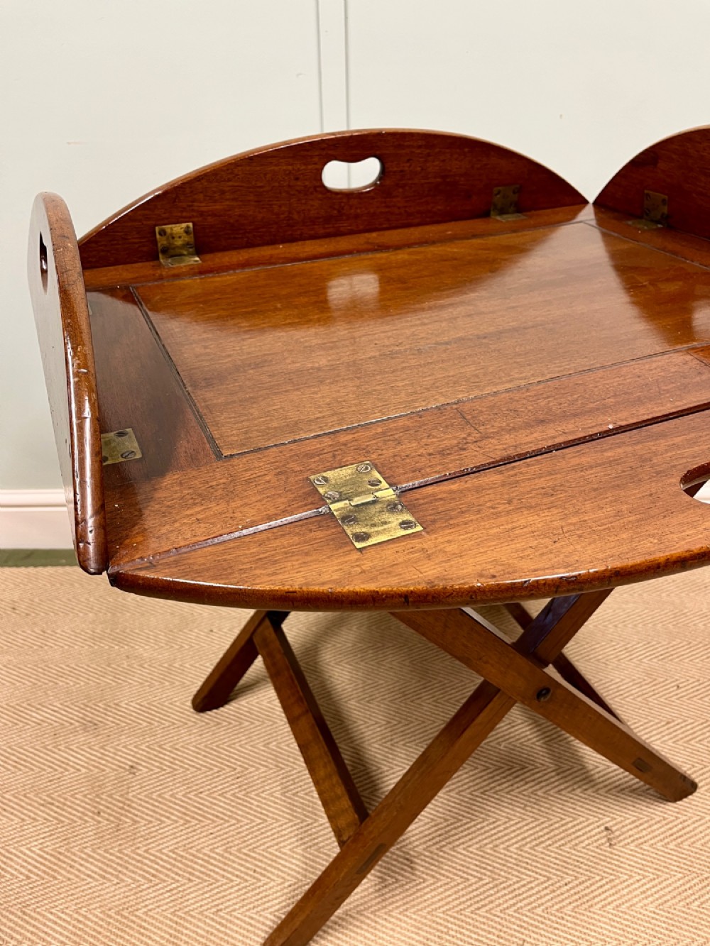 A 19th-century mahogany butlers tray featuring hinged drop sides and hand-cut handles set on a matching folding X-frame stand. View III