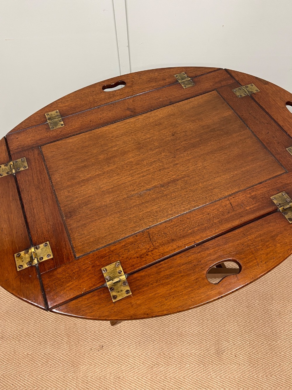 A 19th-century mahogany butlers tray featuring hinged drop sides and hand-cut handles set on a matching folding X-frame stand. View VI