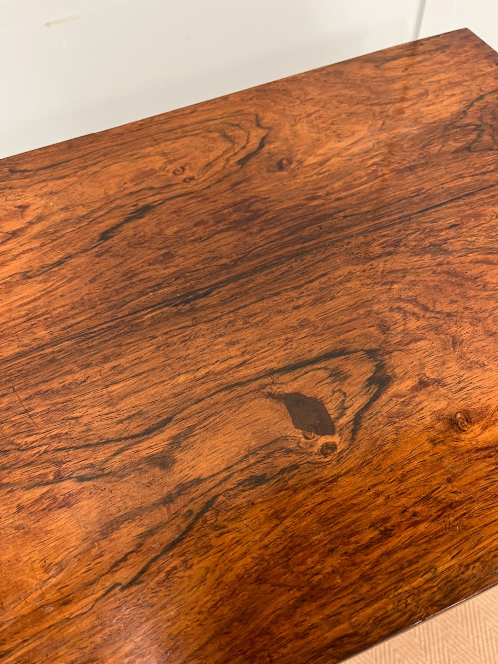 A 19th-century rosewood games table with a polished rectangular fold-over top, a faceted pedestal column, and a quadform base on flattened bun feet. View V