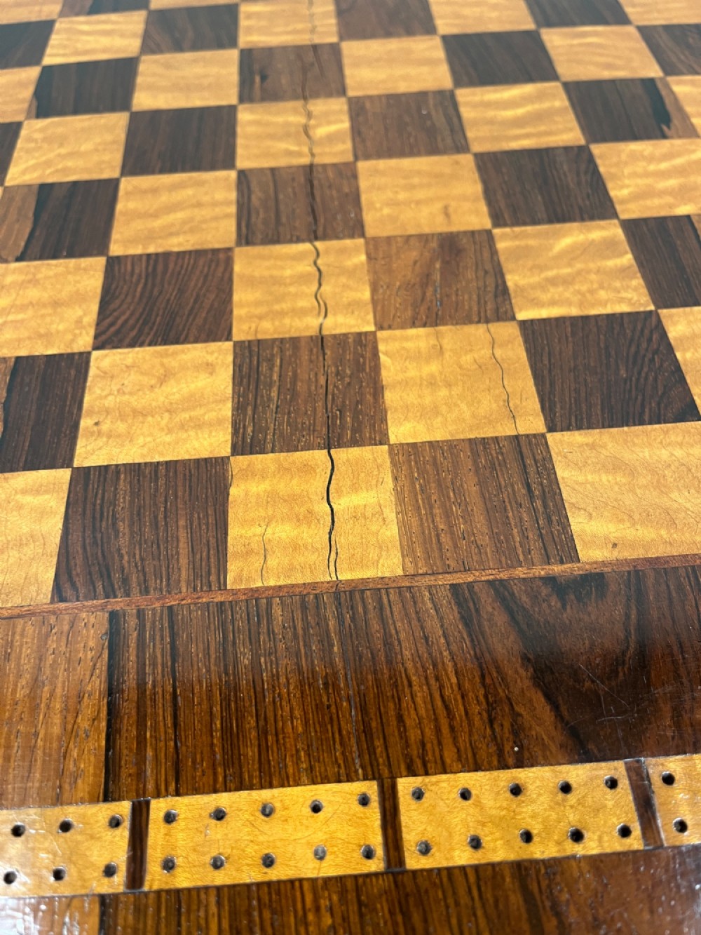 A 19th-century rosewood games table with a polished rectangular fold-over top, a faceted pedestal column, and a quadform base on flattened bun feet. View VIII