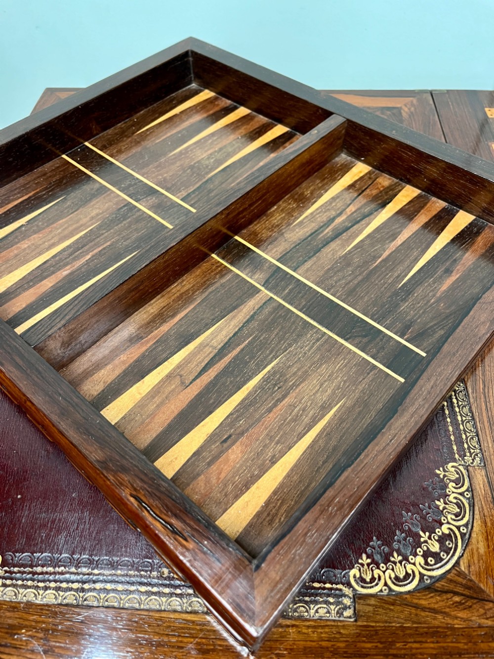 A 19th-century rosewood games table with a polished rectangular fold-over top, a faceted pedestal column, and a quadform base on flattened bun feet. View XII