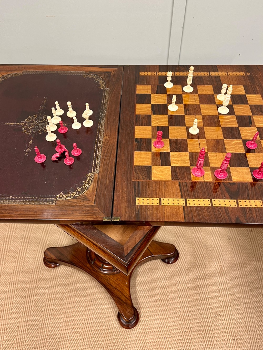 A 19th-century rosewood games table with a polished rectangular fold-over top, a faceted pedestal column, and a quadform base on flattened bun feet. View XIII
