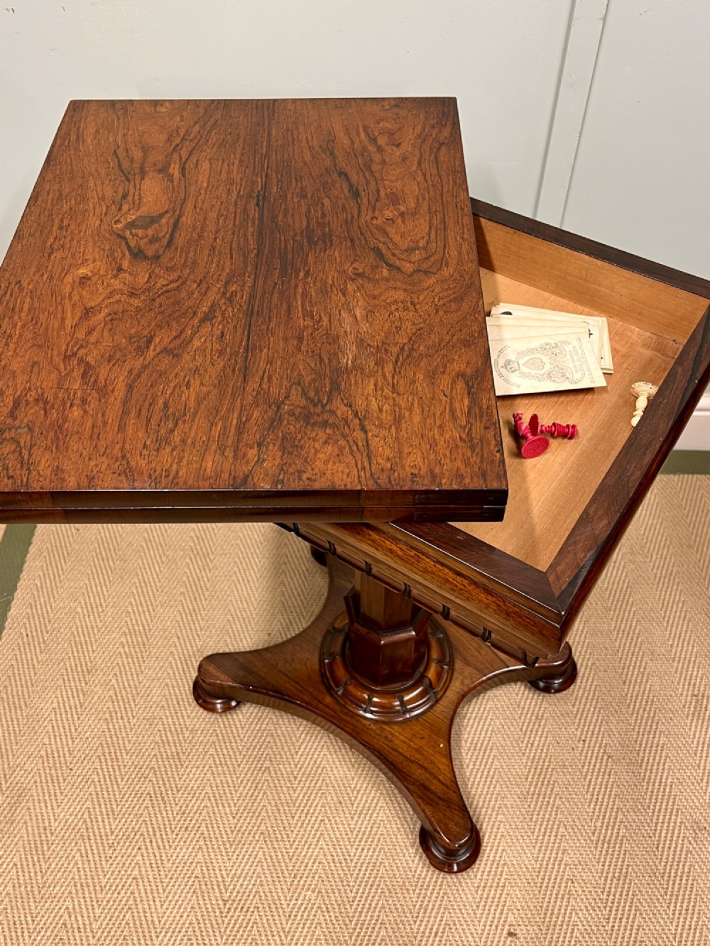 A 19th-century rosewood games table with a polished rectangular fold-over top, a faceted pedestal column, and a quadform base on flattened bun feet. View XV