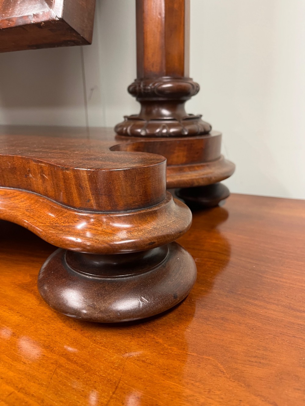 A 19th-century mahogany swing toilet mirror featuring carved support columns, two attached brass candle sconces, and a serpentine plinth base. View V