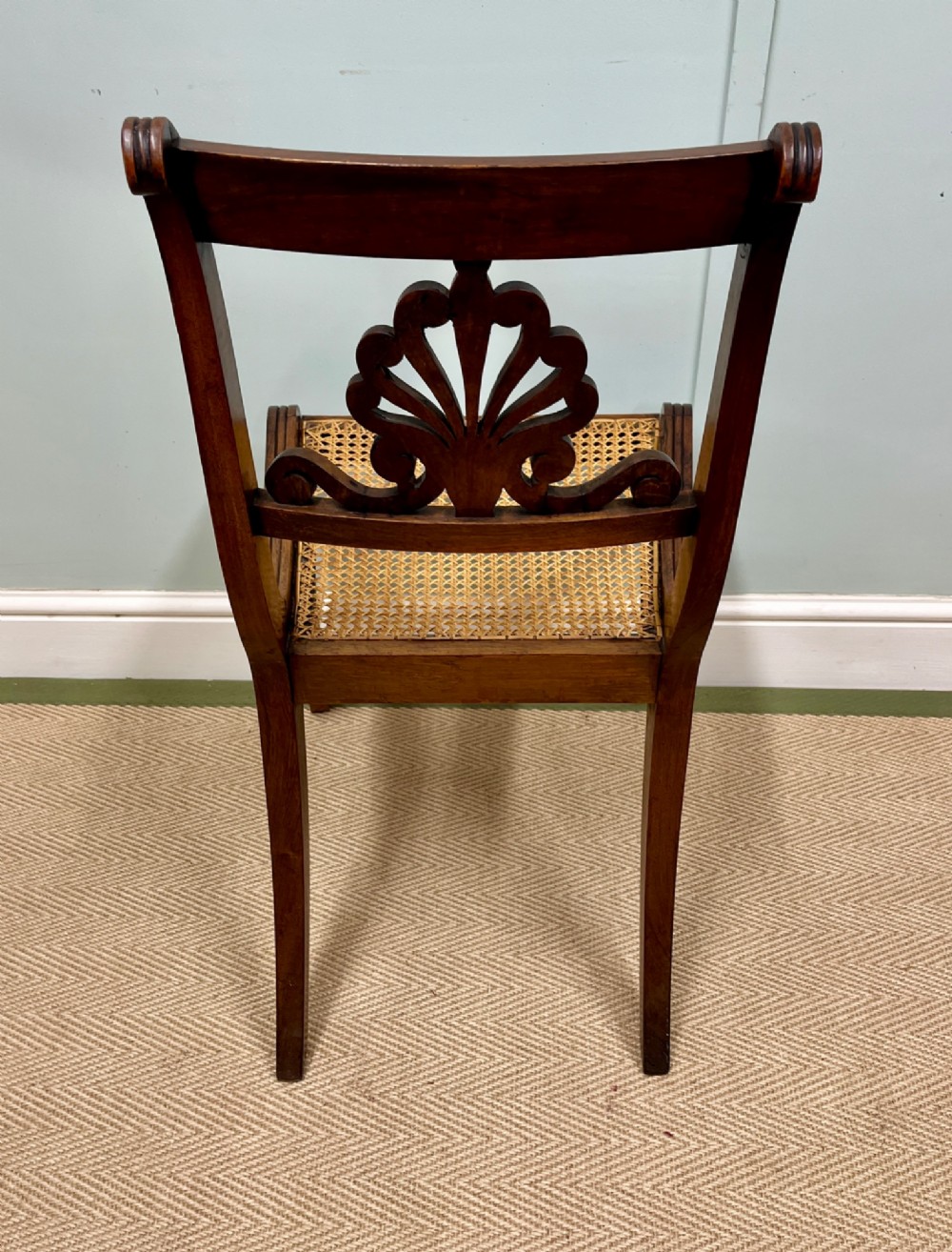 A set of six Regency carved rosewood dining chairs featuring carved anthemion back splats, sabre legs, and woven cane seats. View IX