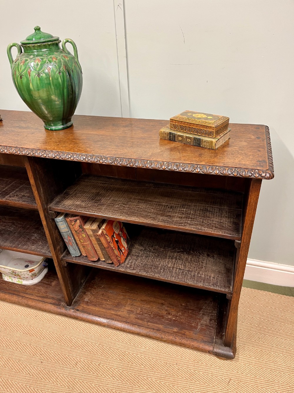 A low nineteenth-century open teak bookcase featuring two main sections with adjustable shelves and a carved egg-and-dart moulding along the top rim. View VI