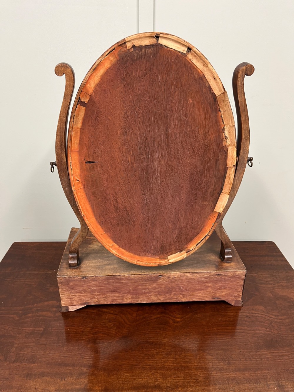 An antique Georgian mahogany toilet mirror featuring an oval adjustable glass frame mounted on curved supports above a three-drawer box base. View VI