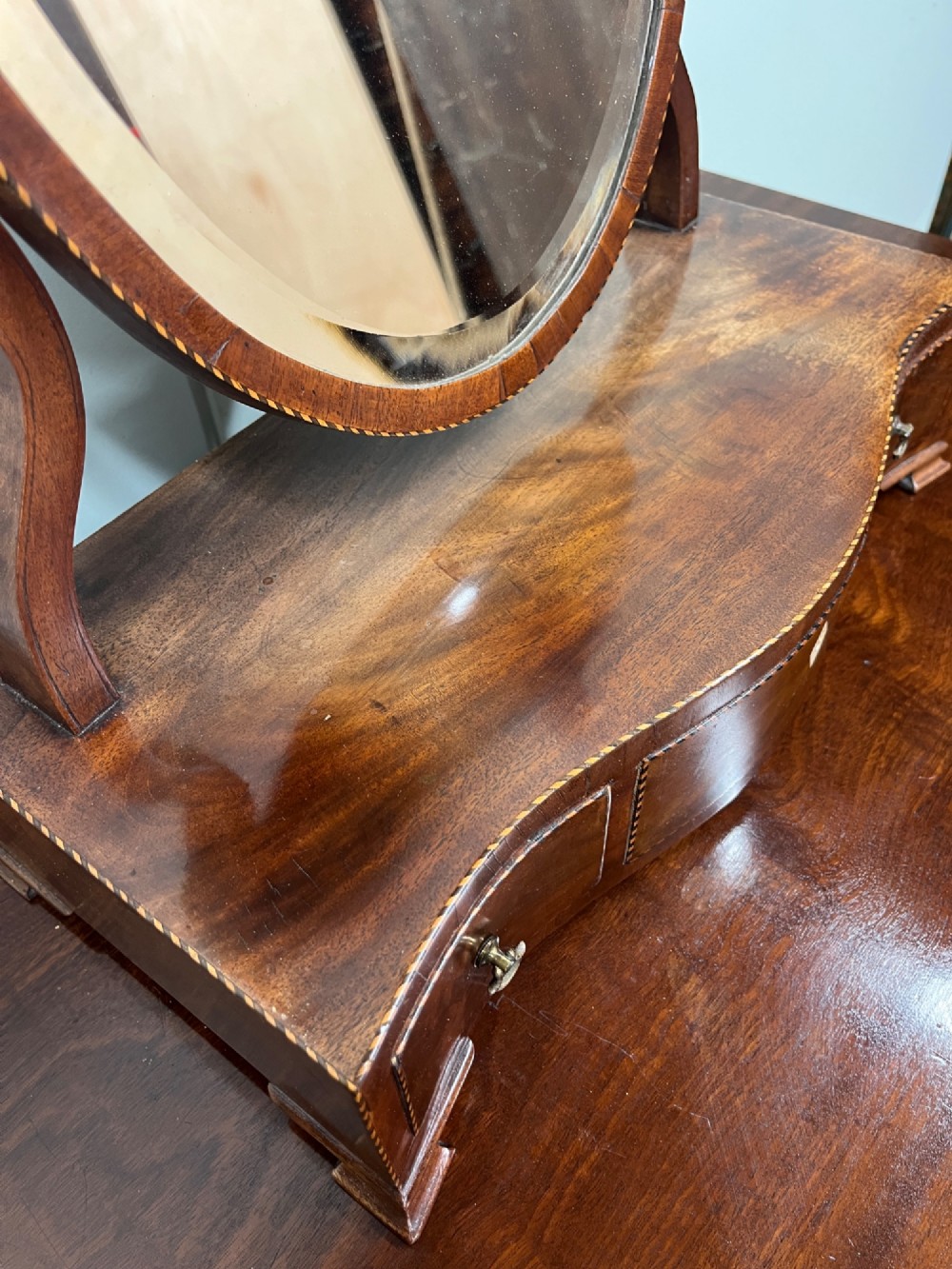 An antique Georgian mahogany toilet mirror featuring an oval adjustable glass frame mounted on curved supports above a three-drawer box base. View VII