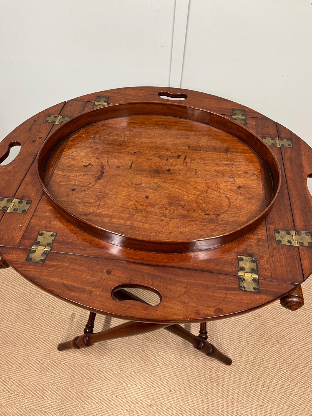 A 19th-century mahogany butlers tray with drop-down hinged sides and cutout hand-holes, set upon a turned folding X-frame stand. View IV