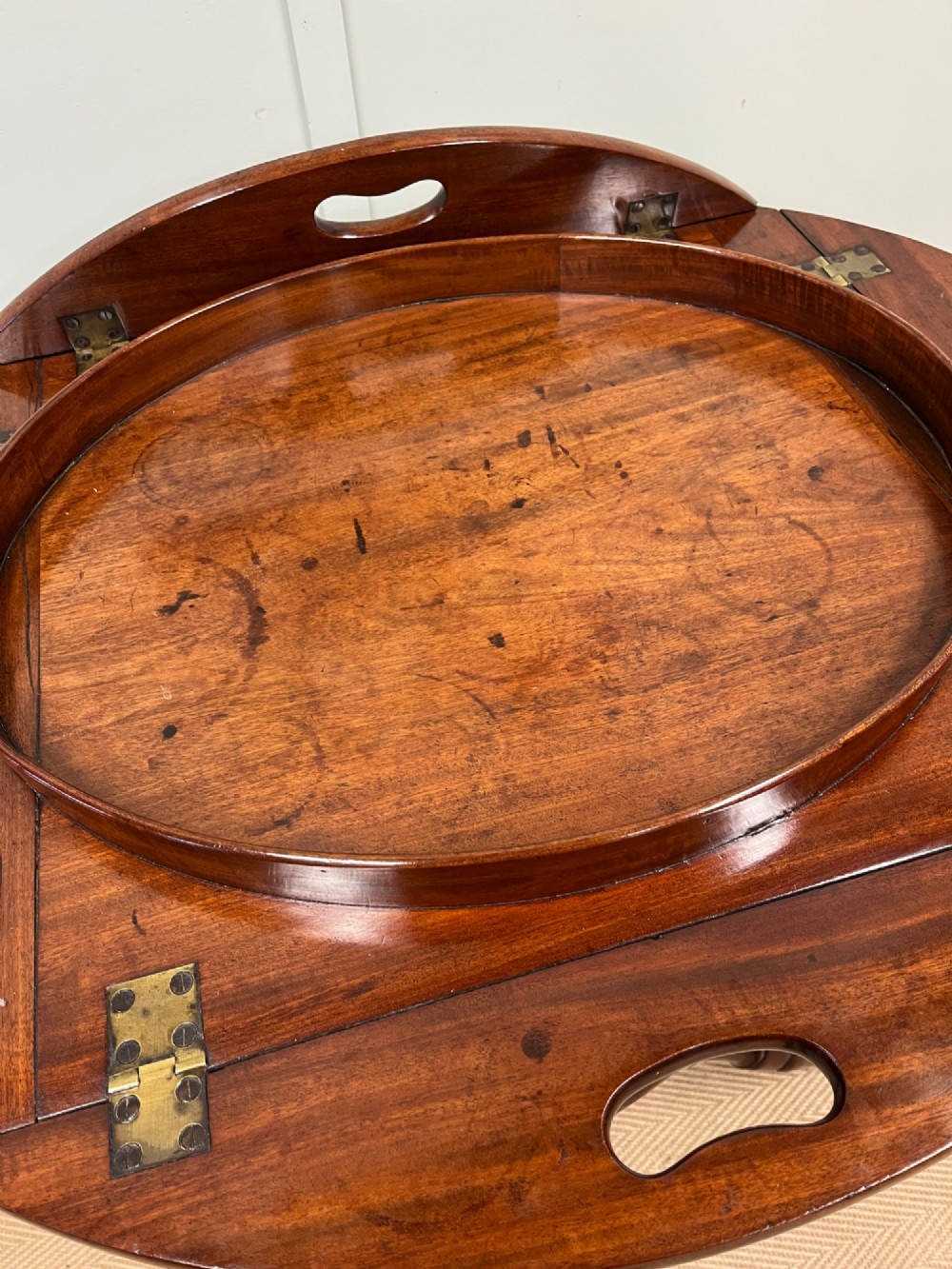 A 19th-century mahogany butlers tray with drop-down hinged sides and cutout hand-holes, set upon a turned folding X-frame stand. View V