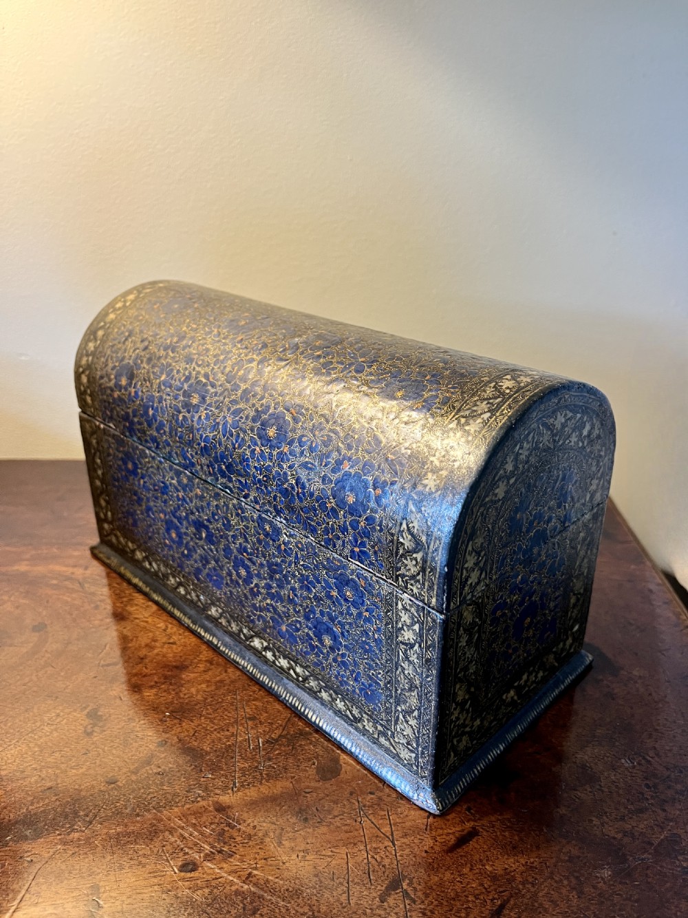 A 19th-century Kashmiri domed papier-mache box featuring detailed blue and gold floral hand-painted motifs with a decorative cream border. View II