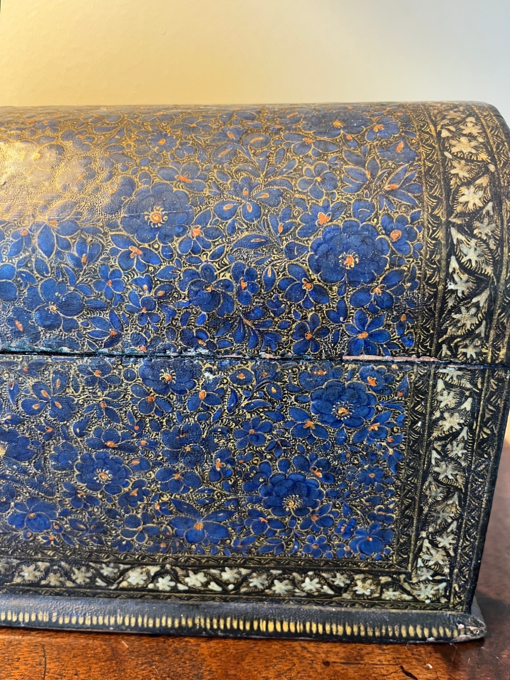 A 19th-century Kashmiri domed papier-mache box featuring detailed blue and gold floral hand-painted motifs with a decorative cream border. View VI