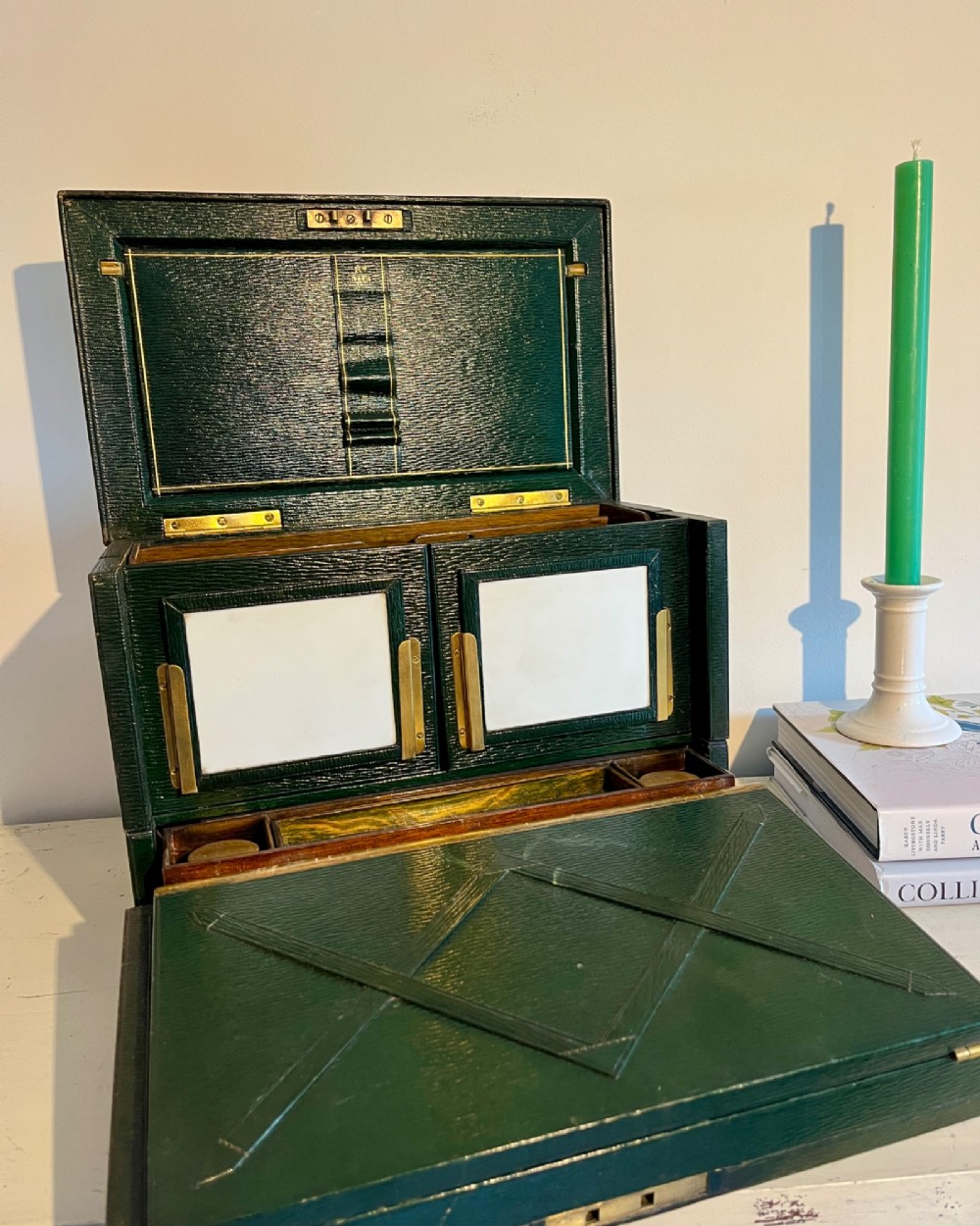 An open nineteenth-century dark green leather stationery box featuring brass fittings, interior memo panels, and compartmentalised sections.